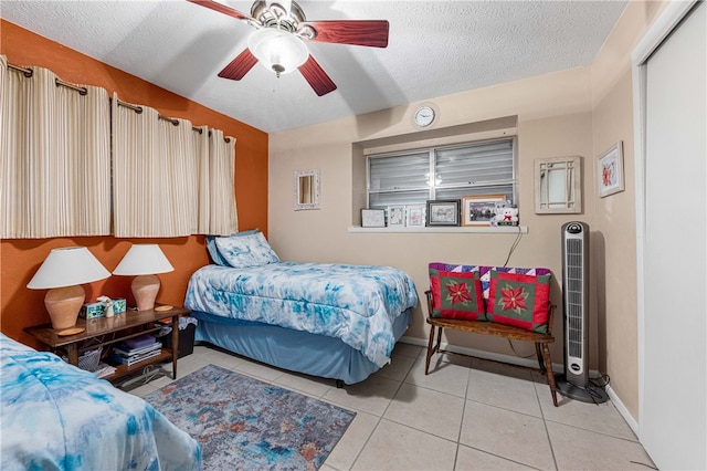 tiled bedroom featuring ceiling fan and a textured ceiling