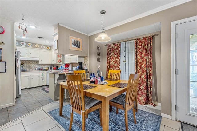 tiled dining area with a textured ceiling and crown molding