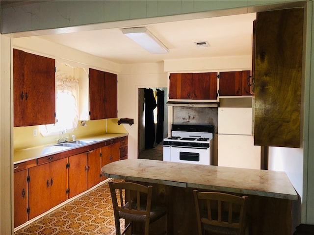 kitchen featuring white appliances, sink, and a kitchen breakfast bar