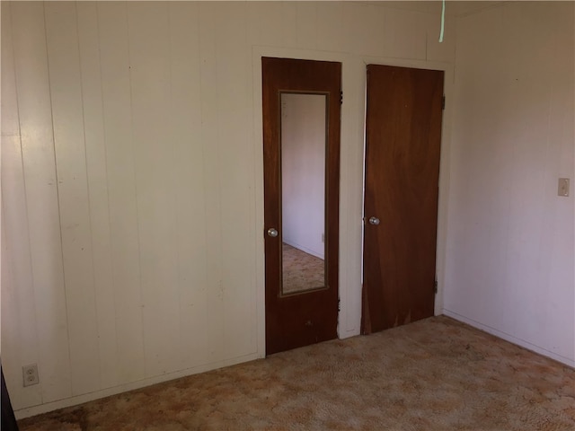 carpeted spare room with wooden walls