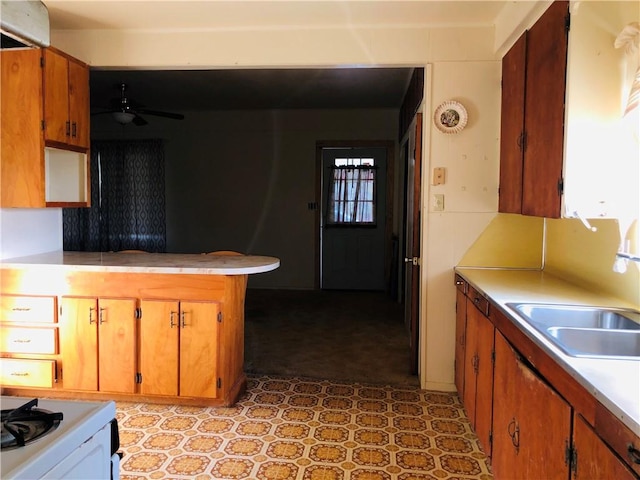 1408 S Norton Hwy, Freer, TX 78357 - kitchen featuring light flooring, ceiling fan, brown cabinets, a sink, and a peninsula