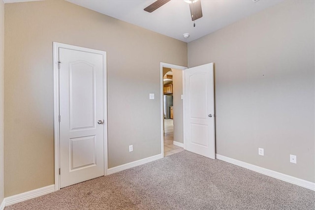 unfurnished bedroom featuring light carpet, stainless steel refrigerator, and ceiling fan