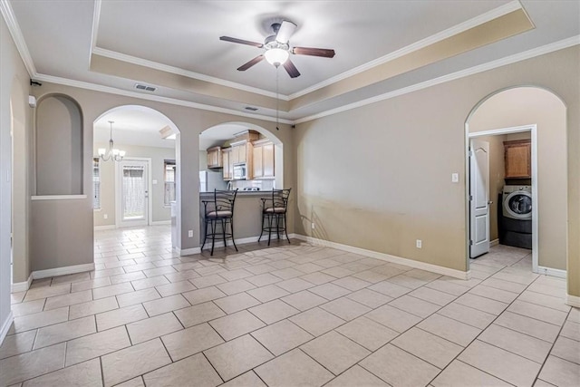 interior space with light tile patterned flooring, ceiling fan, a raised ceiling, and washer / dryer