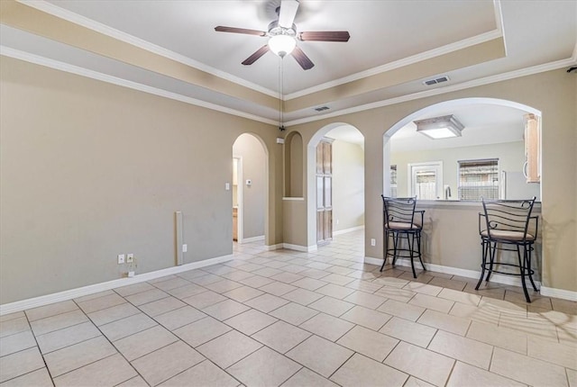 tiled spare room featuring a raised ceiling, ornamental molding, and ceiling fan