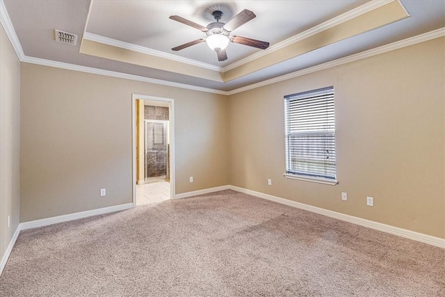 carpeted spare room featuring crown molding, a tray ceiling, and ceiling fan