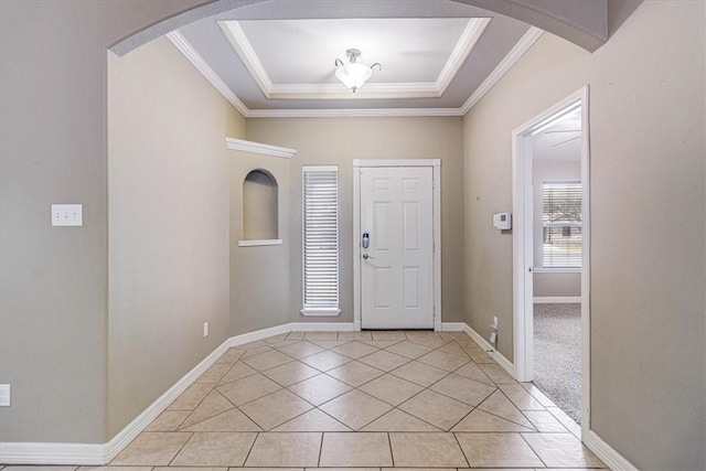 entrance foyer with a tray ceiling, ornamental molding, and light tile patterned flooring