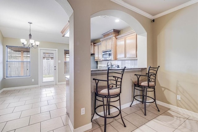 kitchen featuring pendant lighting, a kitchen breakfast bar, light tile patterned flooring, decorative backsplash, and light brown cabinets