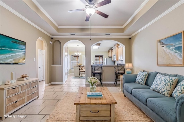 living room featuring a raised ceiling, ornamental molding, ceiling fan with notable chandelier, and light tile patterned flooring