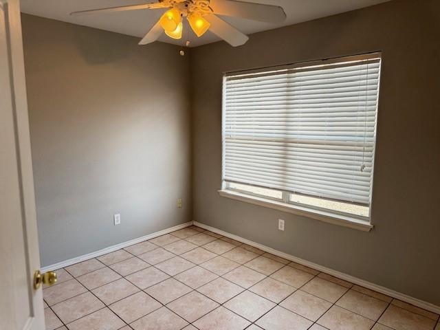 tiled empty room with ceiling fan and a healthy amount of sunlight