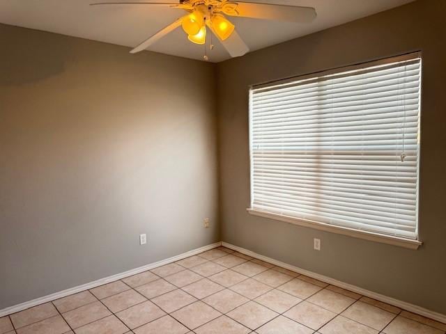 tiled spare room featuring ceiling fan and a healthy amount of sunlight