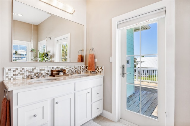 bathroom featuring vanity, tile patterned flooring, a healthy amount of sunlight, and backsplash