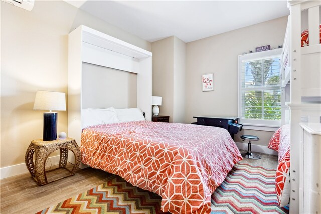 bedroom featuring an AC wall unit and hardwood / wood-style flooring