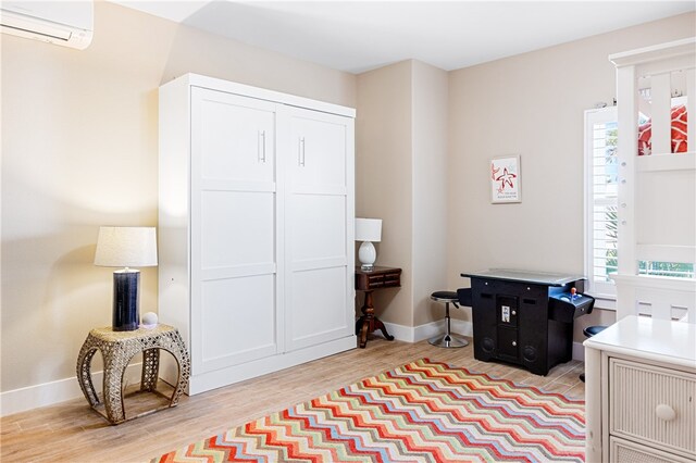 interior space featuring light wood-type flooring, a wall mounted air conditioner, and a healthy amount of sunlight