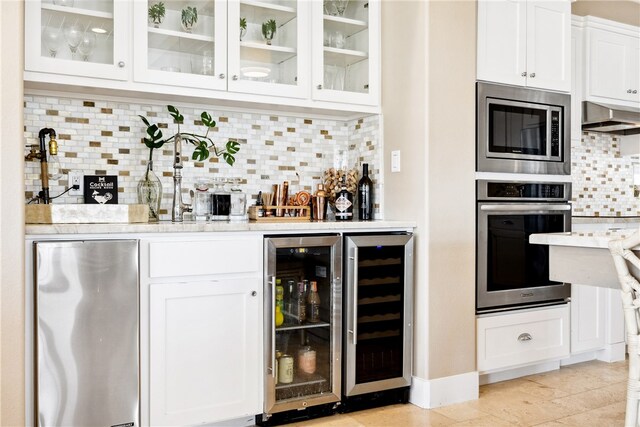 bar with wine cooler, white cabinetry, backsplash, and stainless steel appliances