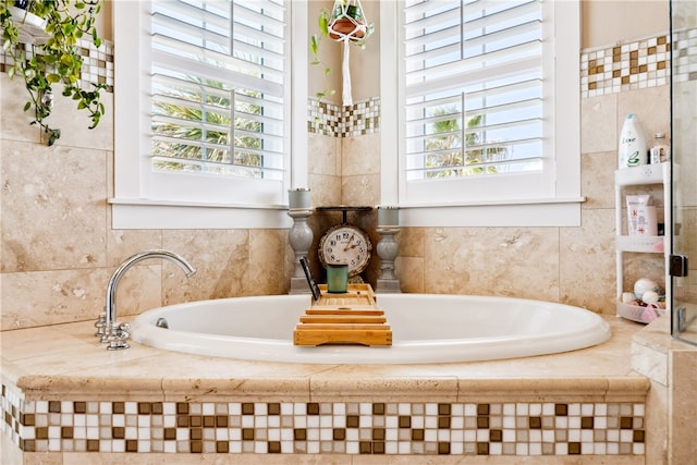 bathroom with tiled bath and a healthy amount of sunlight