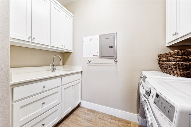 laundry area with cabinets, sink, electric panel, washing machine and dryer, and light wood-type flooring