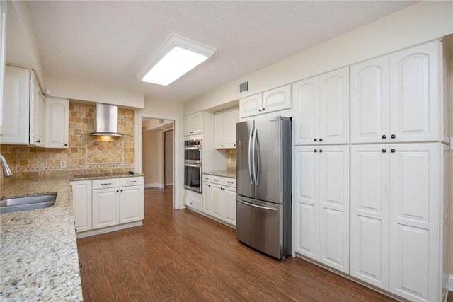 kitchen with wall chimney exhaust hood, sink, white cabinetry, and stainless steel appliances