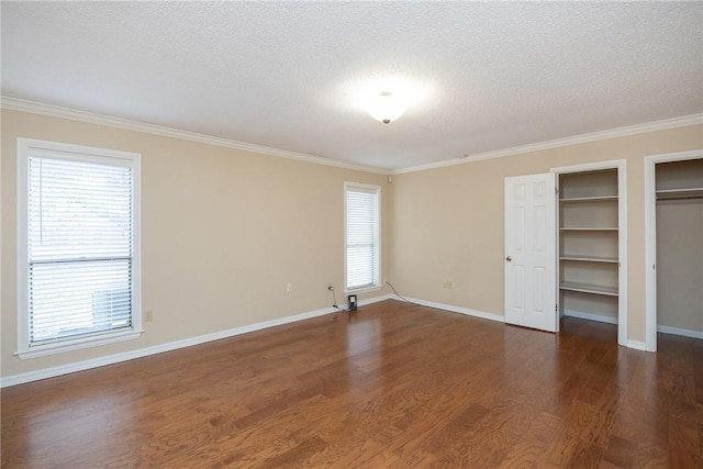 unfurnished bedroom with dark hardwood / wood-style floors, ornamental molding, a textured ceiling, and multiple windows