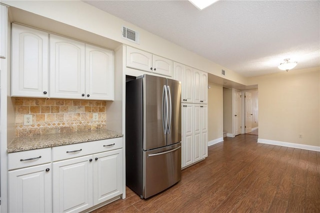 kitchen featuring dark hardwood / wood-style floors, white cabinetry, backsplash, and stainless steel refrigerator