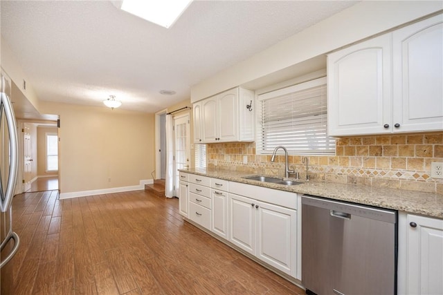 kitchen with light stone countertops, appliances with stainless steel finishes, tasteful backsplash, sink, and white cabinets