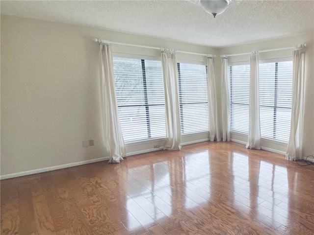 empty room featuring a textured ceiling and light hardwood / wood-style floors