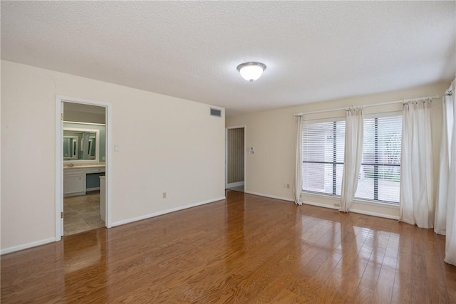 empty room featuring a textured ceiling and dark hardwood / wood-style floors