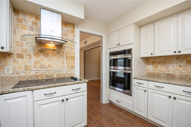 kitchen with white cabinets, black electric cooktop, dark hardwood / wood-style flooring, stainless steel double oven, and extractor fan