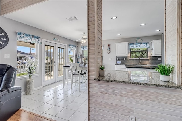 kitchen featuring dark stone counters, french doors, ceiling fan, decorative backsplash, and white cabinetry