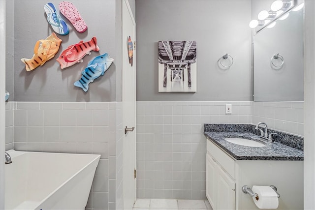 bathroom featuring vanity, tile patterned floors, tile walls, and a bathing tub