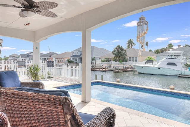 view of pool with a boat dock, a water view, ceiling fan, and a patio area