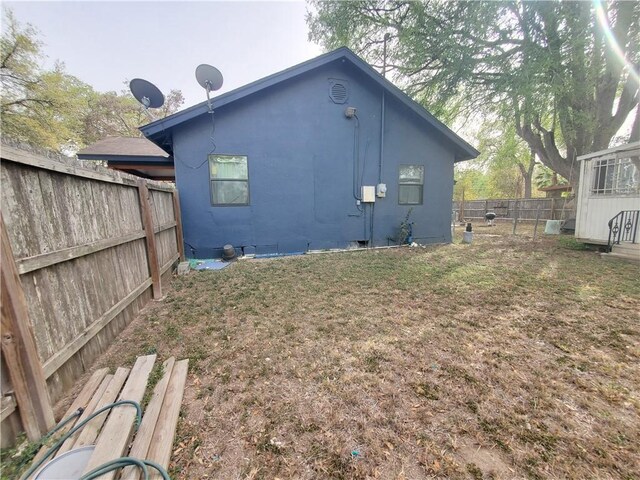 back of house featuring stucco siding, a lawn, and a fenced backyard
