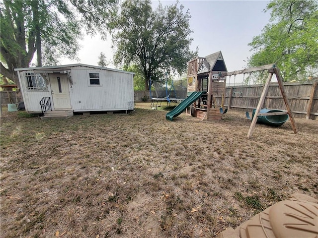 view of playground with a fenced backyard, an outbuilding, and a trampoline