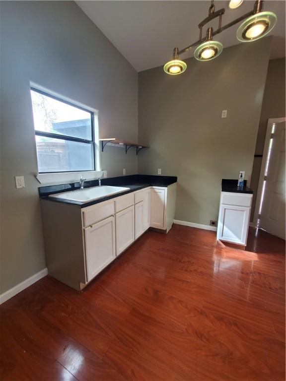 kitchen featuring a sink, baseboards, dark wood-style flooring, and white cabinetry