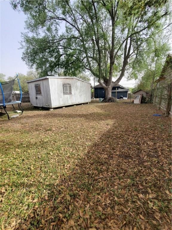 view of yard with an outdoor structure, a trampoline, and a shed