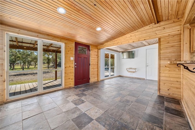 interior space with a healthy amount of sunlight, lofted ceiling with beams, wooden walls, and wooden ceiling