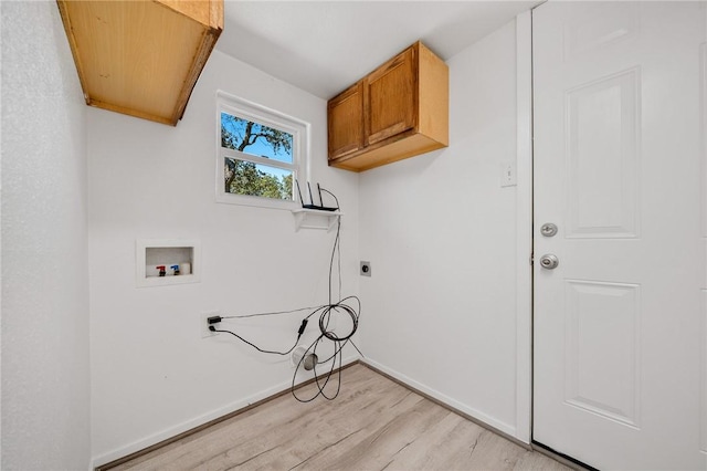 washroom with washer hookup, light hardwood / wood-style floors, and cabinets