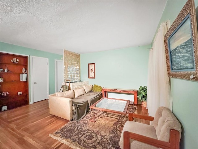 living room featuring light wood-type flooring and a textured ceiling