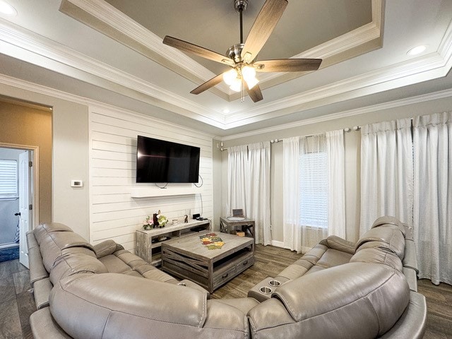 living room with ceiling fan, dark hardwood / wood-style floors, crown molding, and a tray ceiling