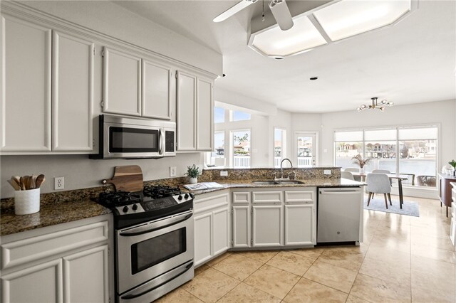 13726 Cayo Gorda Ct, Corpus Christi, TX 78418 - kitchen featuring a peninsula, a sink, dark stone counters, appliances with stainless steel finishes, and light tile patterned flooring
