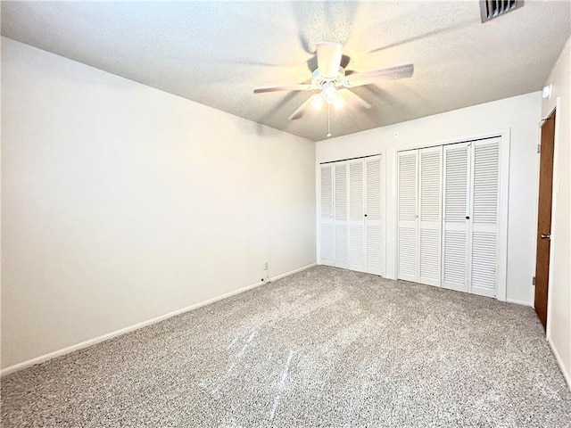 unfurnished bedroom with multiple closets, ceiling fan, carpet floors, and a textured ceiling