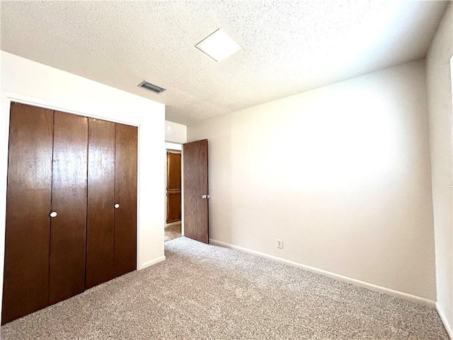 unfurnished bedroom featuring light carpet, a textured ceiling, and a closet