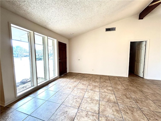 spare room featuring lofted ceiling with beams, light tile patterned floors, and a textured ceiling