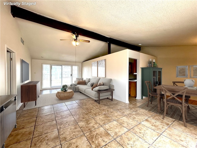 tiled living room with ceiling fan, vaulted ceiling with beams, and a textured ceiling