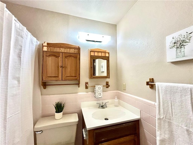 bathroom with vanity, tile walls, and toilet