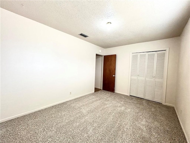 unfurnished bedroom with carpet floors, a textured ceiling, and a closet