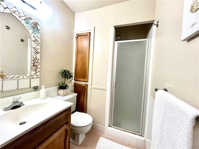 bathroom featuring a shower with door, vanity, tile patterned floors, and toilet