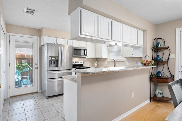 2301 Cyprus Dr, Ingleside, TX 78362 - kitchen with stainless steel appliances, a peninsula, white cabinets, and plenty of natural light