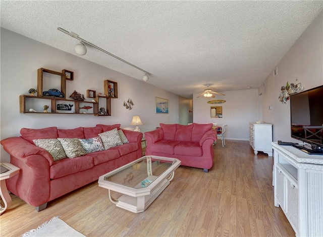 living room featuring track lighting, light hardwood / wood-style flooring, a textured ceiling, and ceiling fan