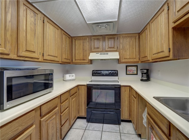 kitchen featuring a textured ceiling, light tile patterned floors, and electric range