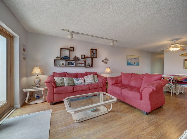 living room featuring light wood-type flooring, a textured ceiling, ceiling fan, and rail lighting